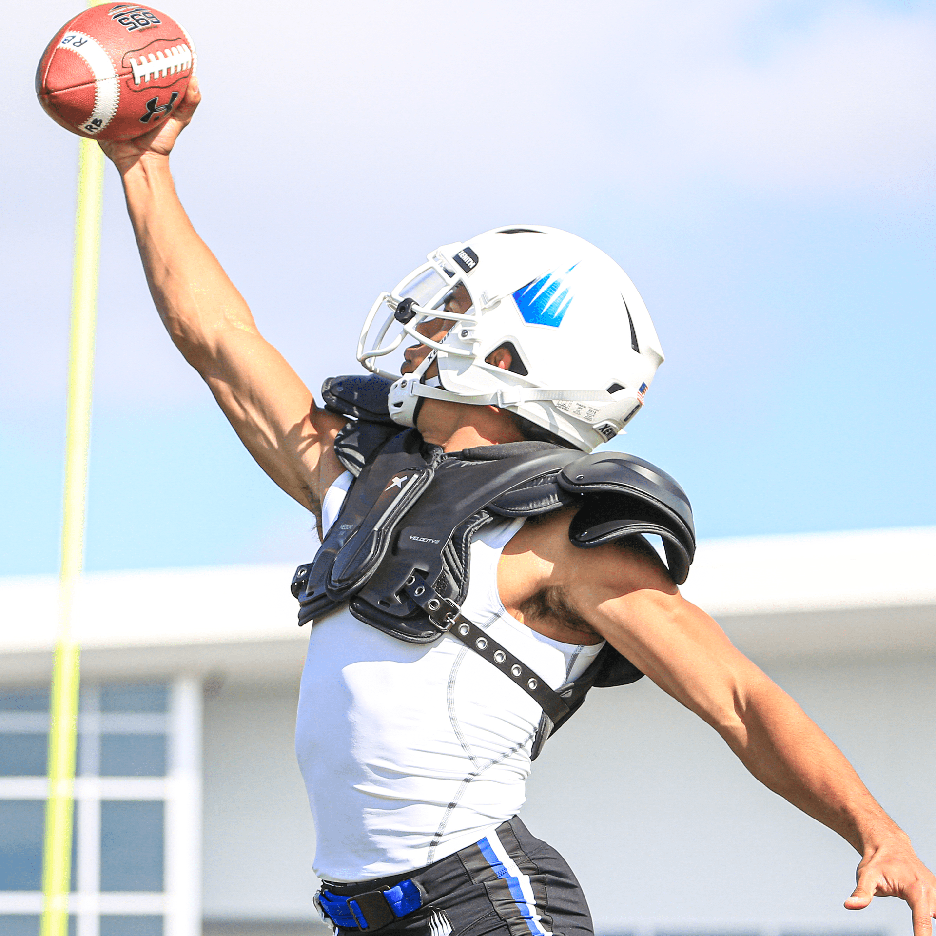 Football player wearing Velocity 2 shoulder pads catching a football.