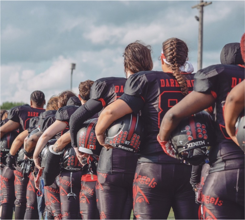 Football players turned with backs facing the camera during the National Anthem.