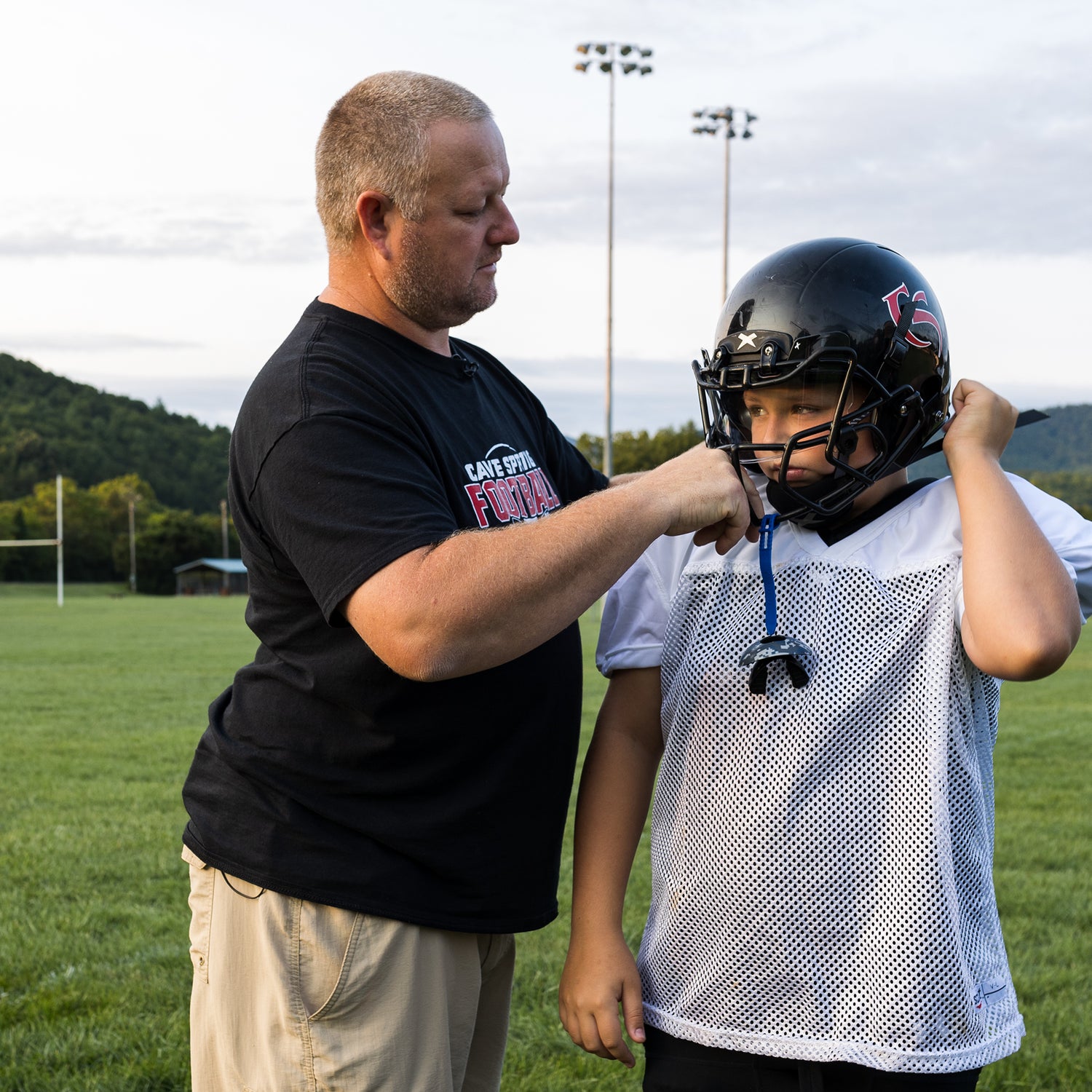 A coach helps to ensure the proper fit of a player's new Xenith Shadow Helmet.