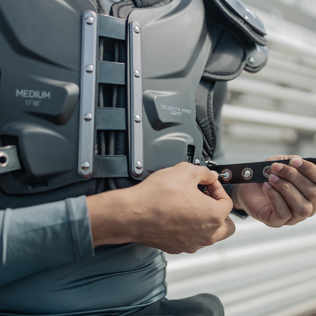 Close up of a player wearing Xenith shoulder pads and pulling the belt strap.