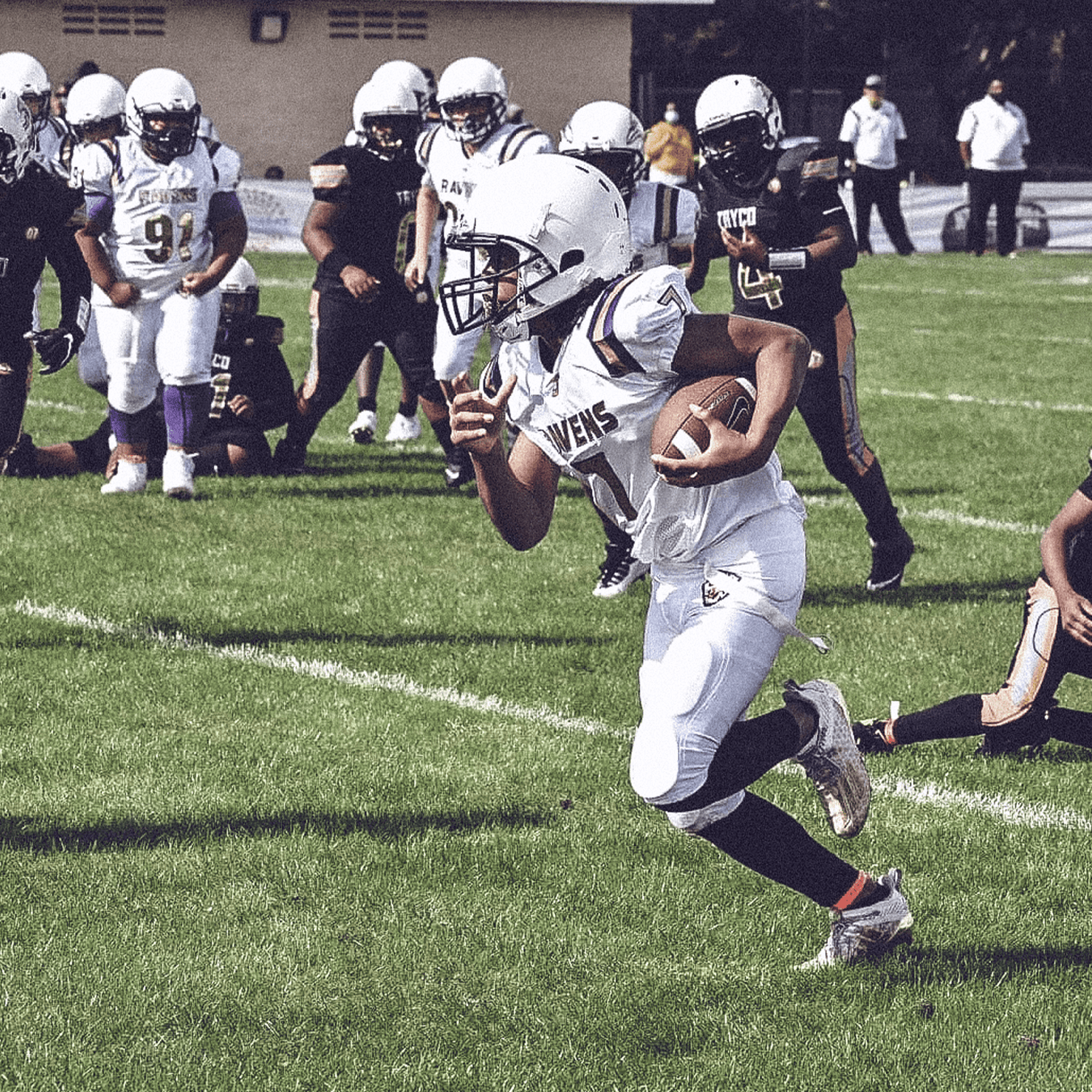 Football player running with football tucked under arm.