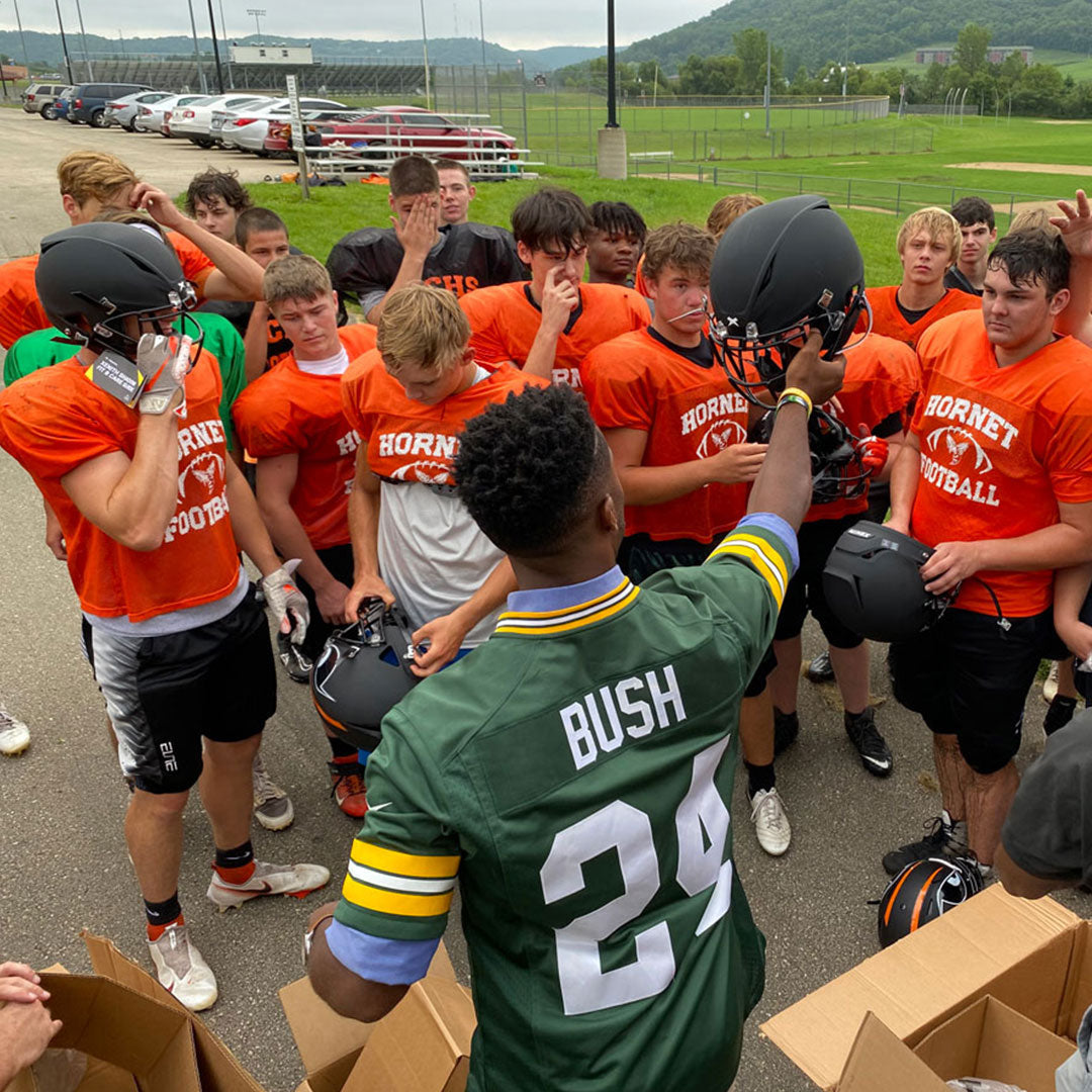 A man handing out Xenith football helmets to football players.