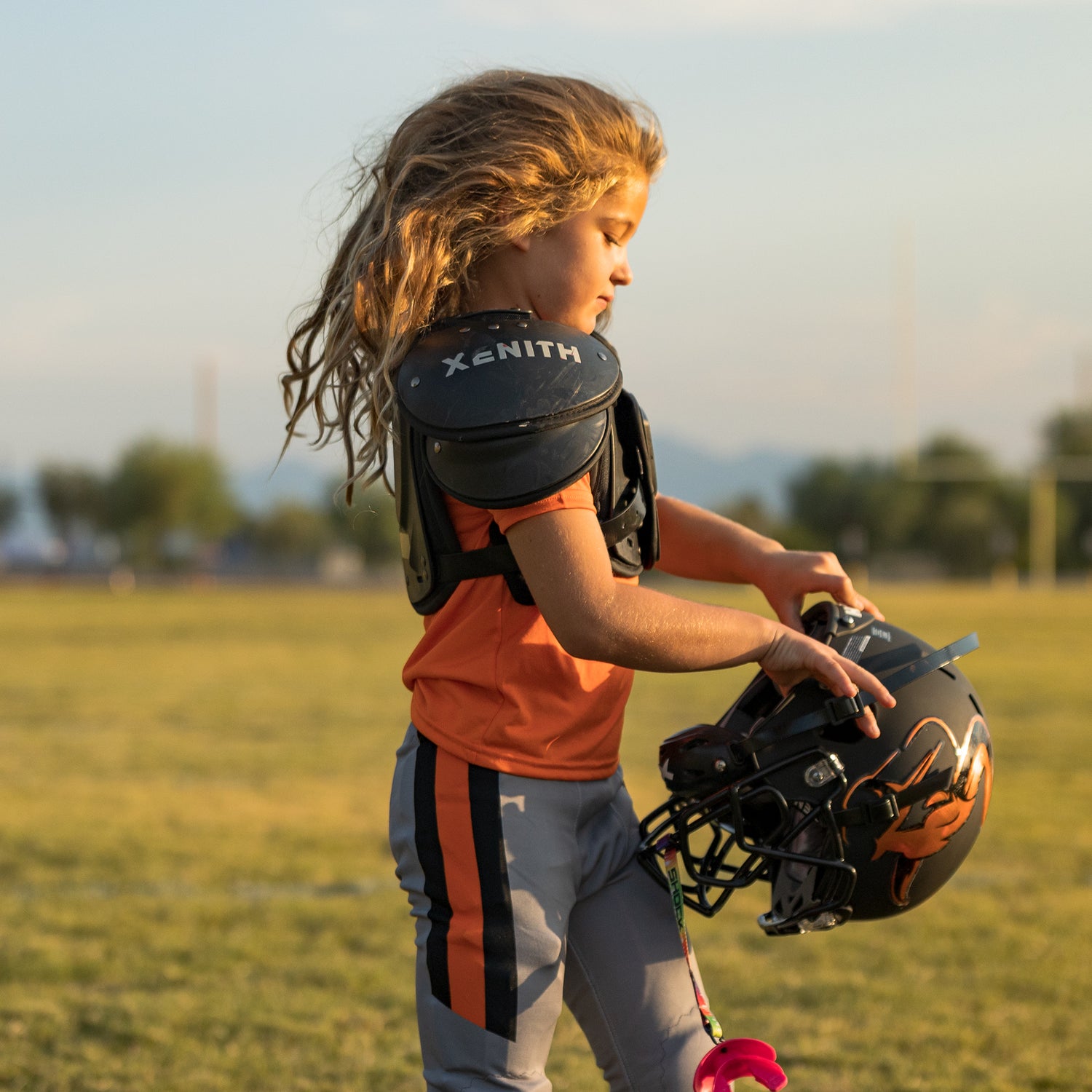 Side-view of a youth football player putting on a helmet.