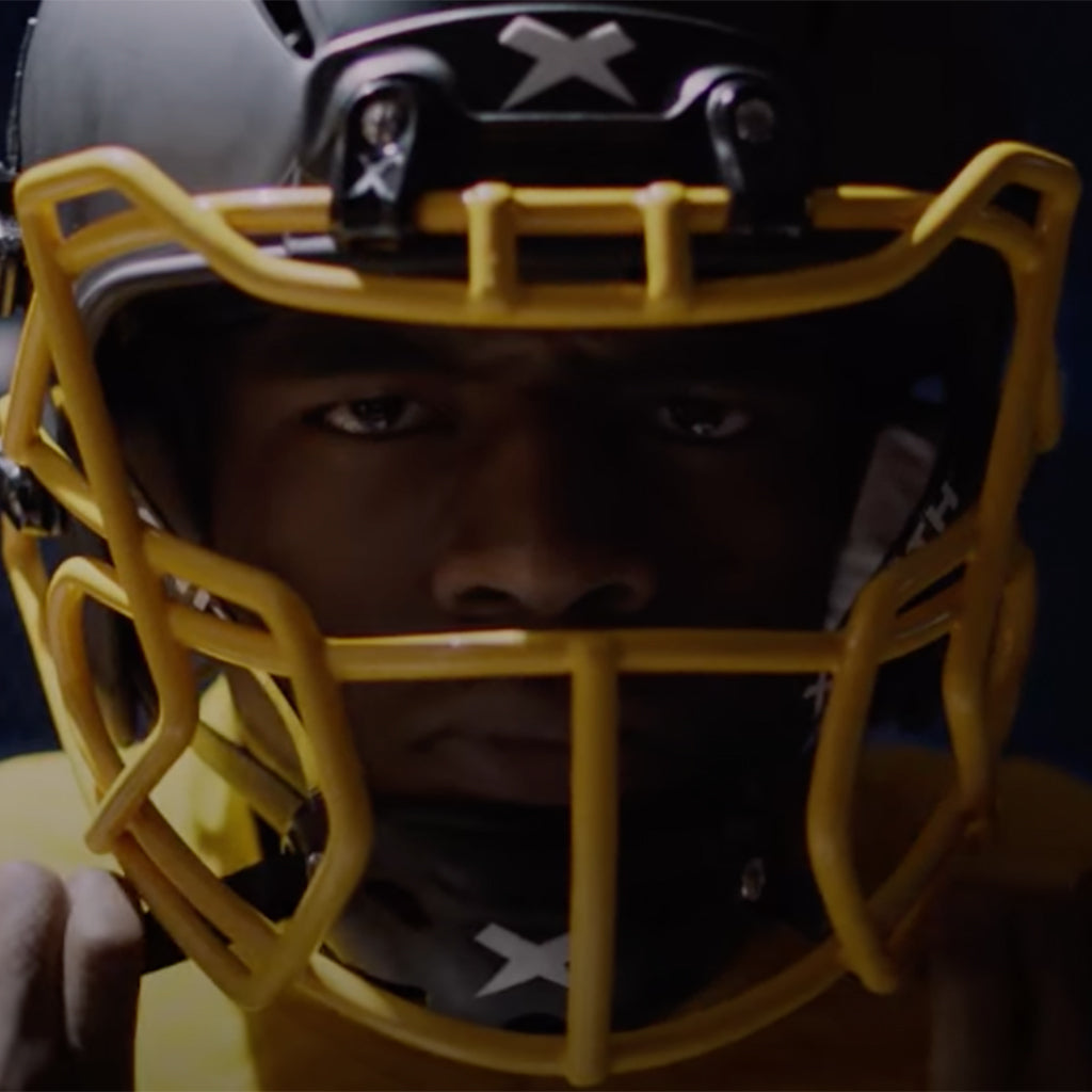 Close up of a football player tightening the chinstrap of a Xenith helmet.