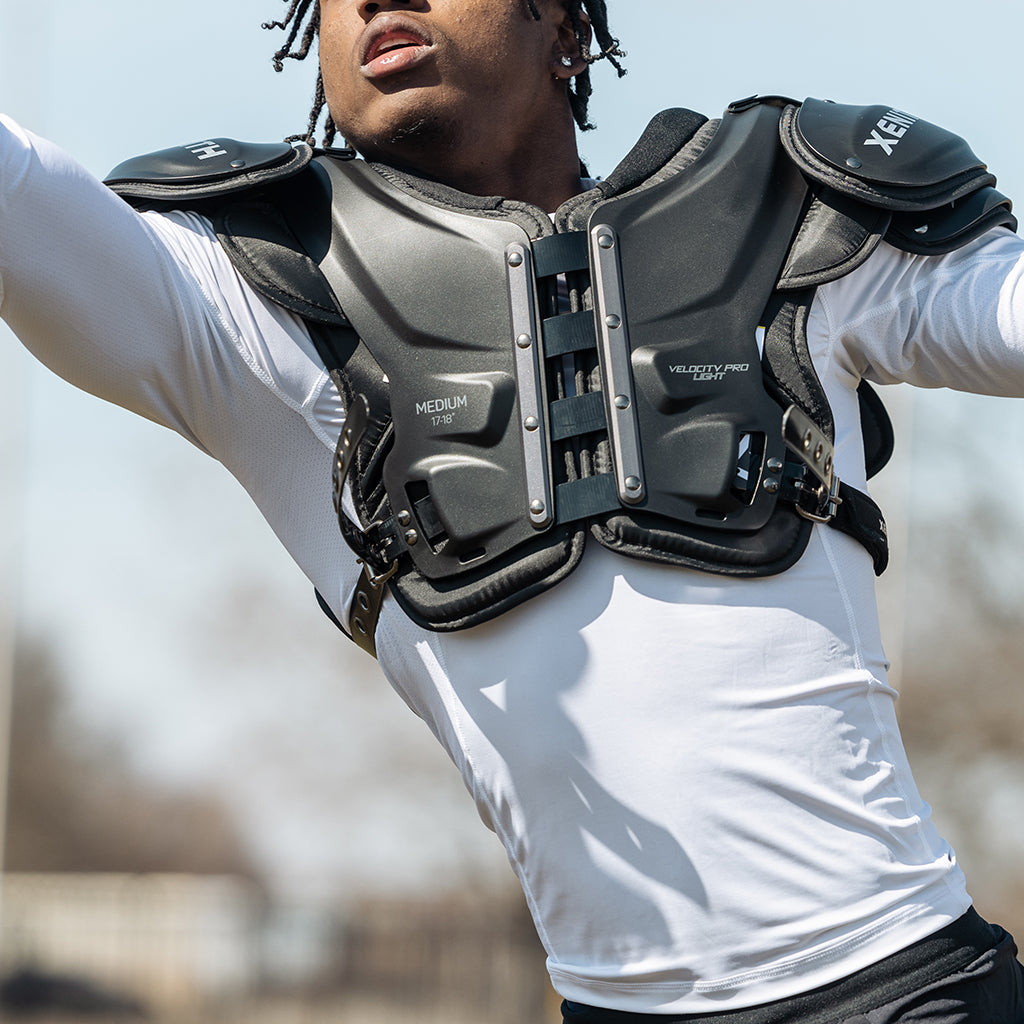 A football player stretching to make a play wearing Xenith Velocity Pro Light shoulder pads.