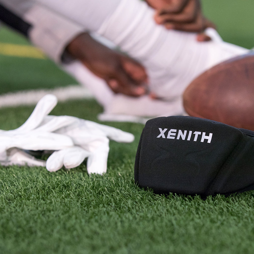 Close up of Xenith Gloves and Xenith LOOP sitting on turf.