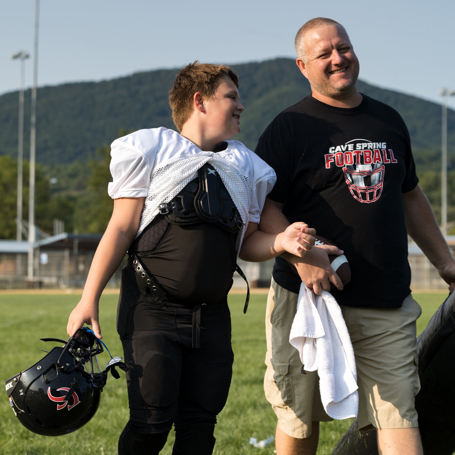 A football player and his father walking off the field after practice.