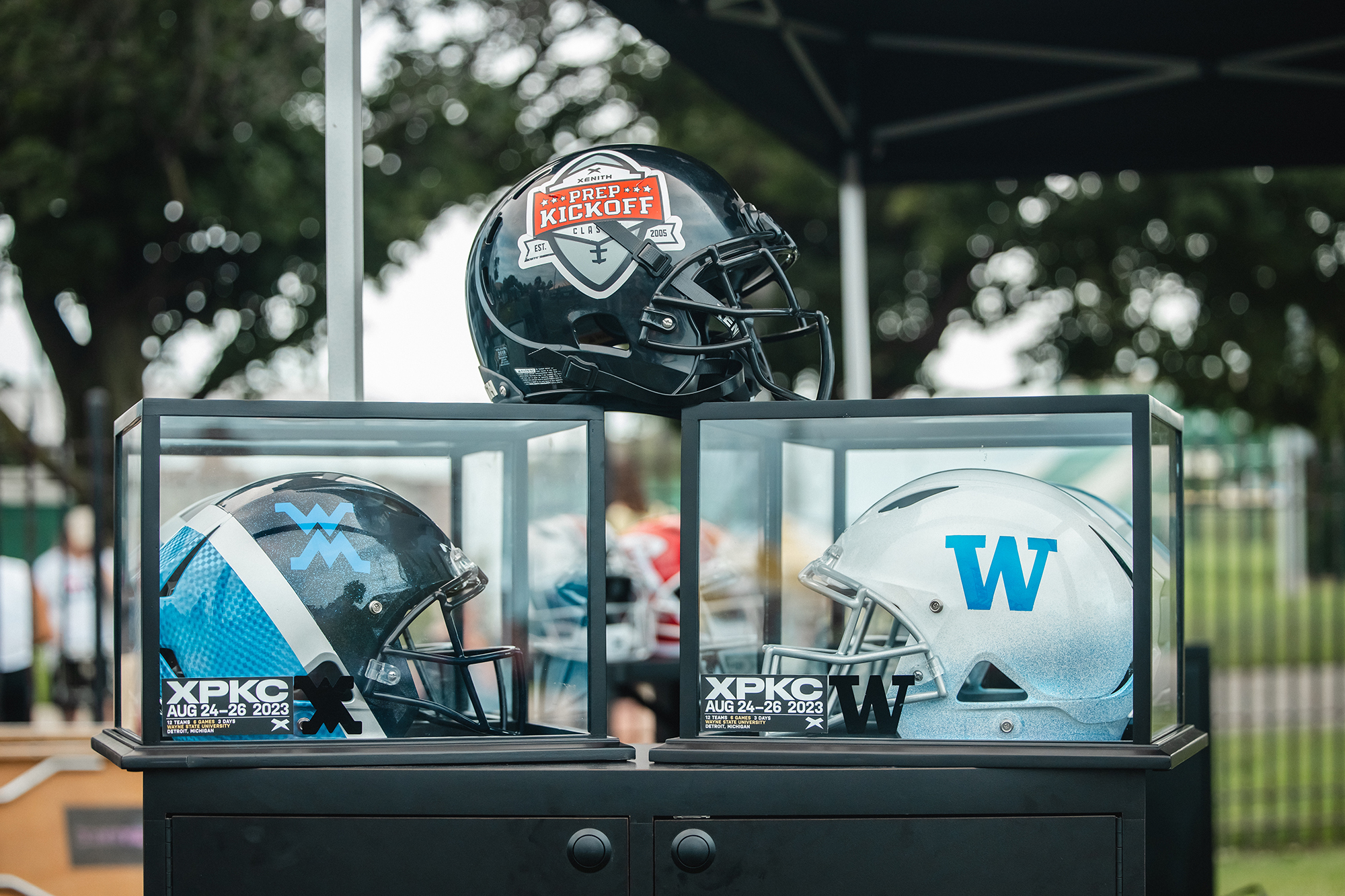 Two Xenith Trophy Helmets Displayed in their cases facing each other.