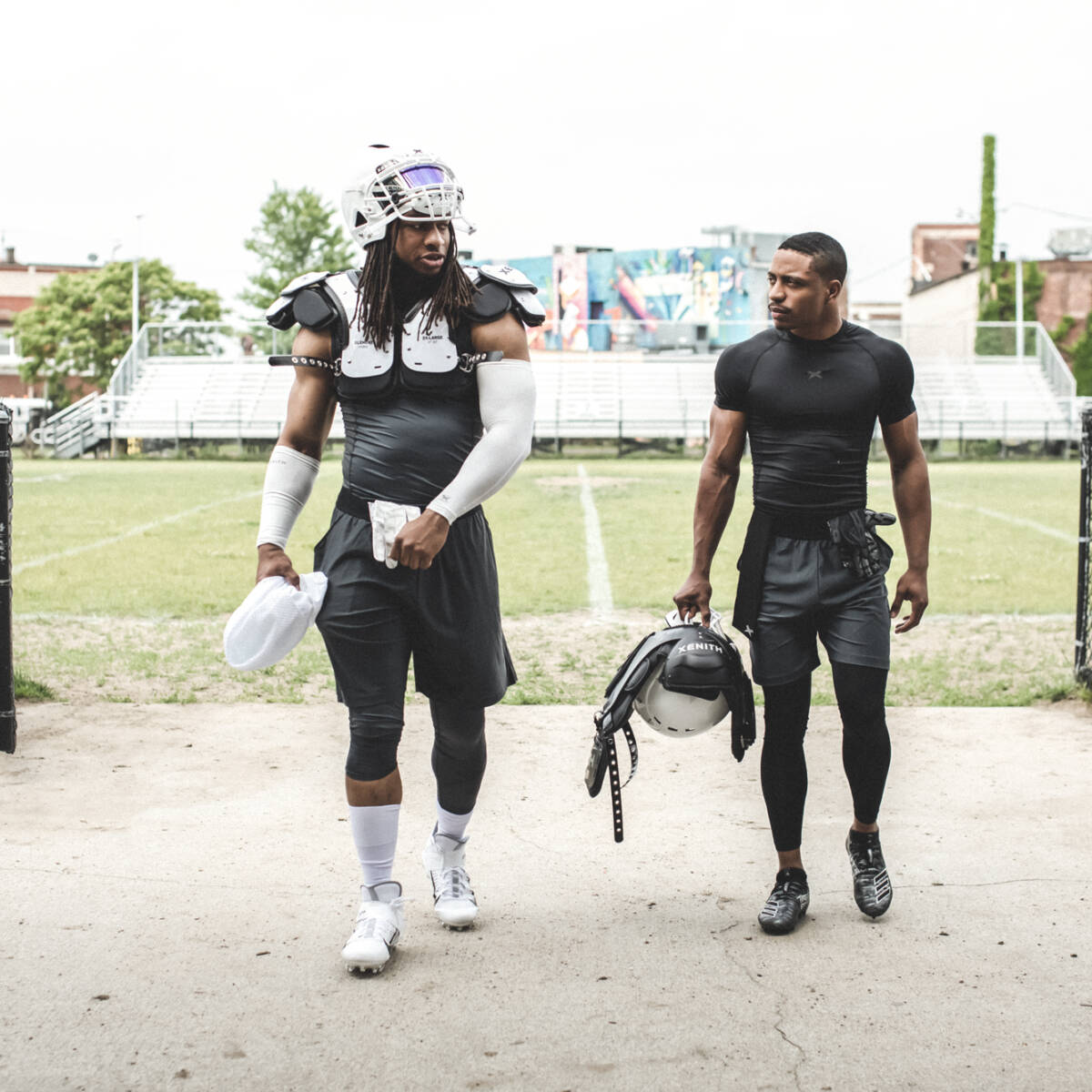 Two athletes walking off the field in partial gear.