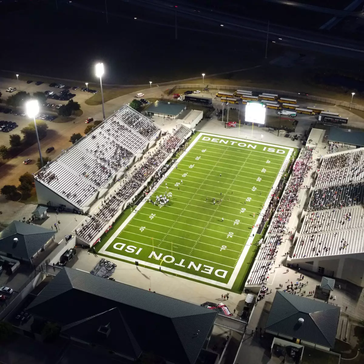 Sky view of a high school football stadium with the lights turned on.