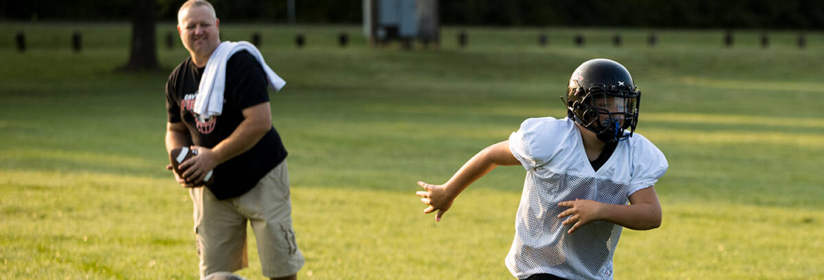 A father and son practicing football drills.