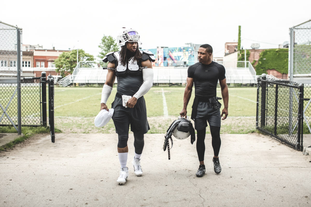 Two athletes walking off the field in partial gear.