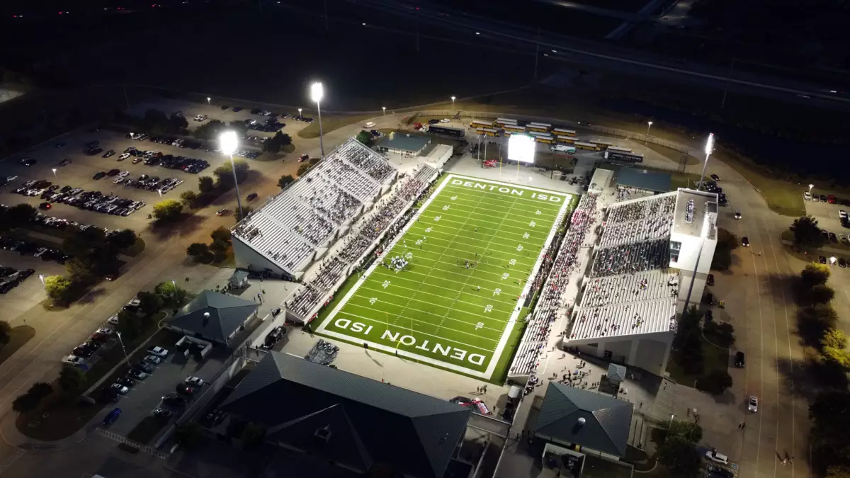 Sky view of a high school football stadium with the lights turned on.