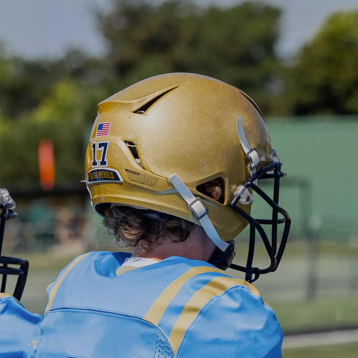Close up of a player looking away from the camera wearing a gold Xenith helmet.