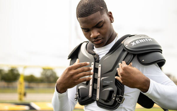 Close-up of a player putting on Xenith shoulder pads.