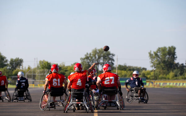 A wheelchair football quarterback throwing a pass down field.
