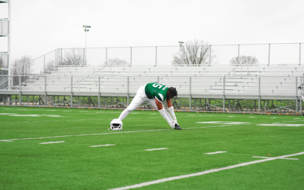 Jalen Thompson stretching on a football field.