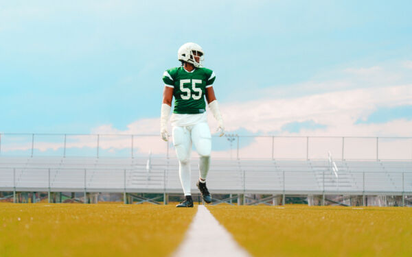 Low shot of Jalen Thompson walking across a football field in full uniform.