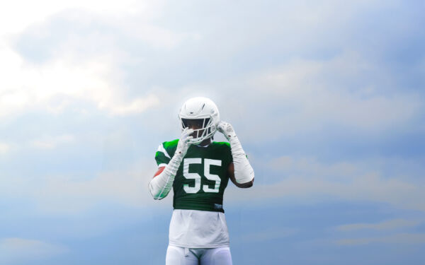 Jalen Thompson standing in front of a cloudy background, facing the camera and adjusting his helmet.