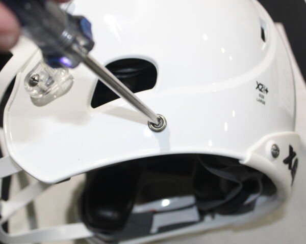 Close up view showing how to remove the screw under the earhole of a Xenith X2E+ helmet.