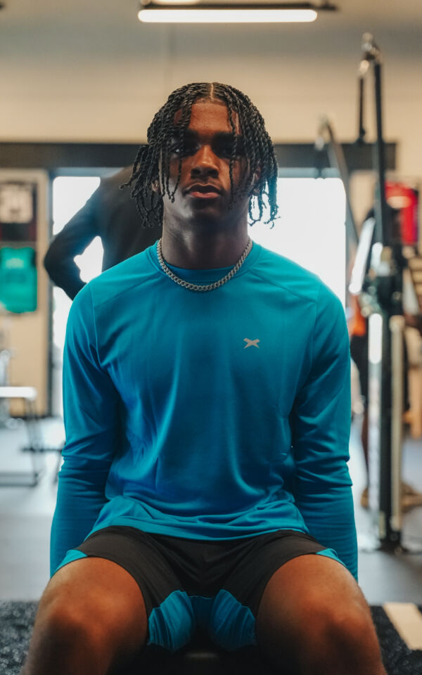 Close up of Prince facing the camera with his arms by his side while lifting weights.