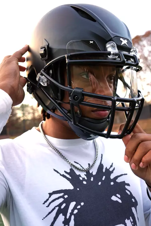 Close up of Tyler Atkinson putting on a black Xenith helmet.