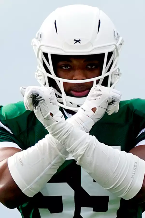 Close up of Jalen Thompson holding his arms up in an X shape while wearing a white Xenith helmet.