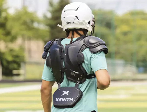 Backside view of a player walking away from the camera wearing Xenith shoulder pads, a Xenith back plate, and a Xenith helmet.