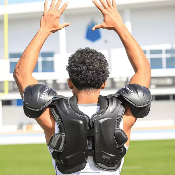 Backside view of player holding his arms above his head while wearing Xenith Velocity 2 shoulder pads.