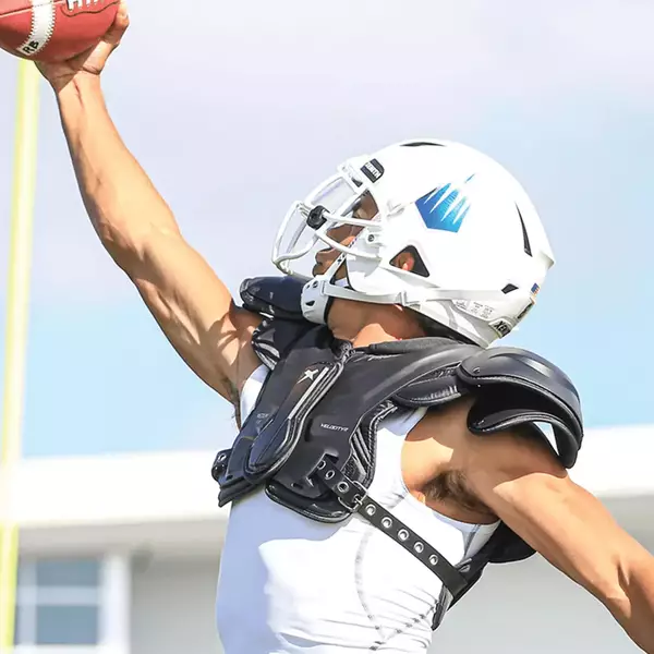 Player catching a pass while wearing Xenith Velocity 2 football shoulder pads.