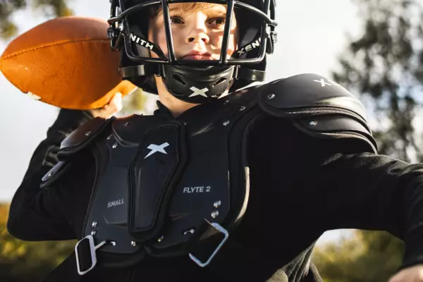 Youth athlete wearing xenith flyte 2 SF football shoulder pads and about to throw a football.